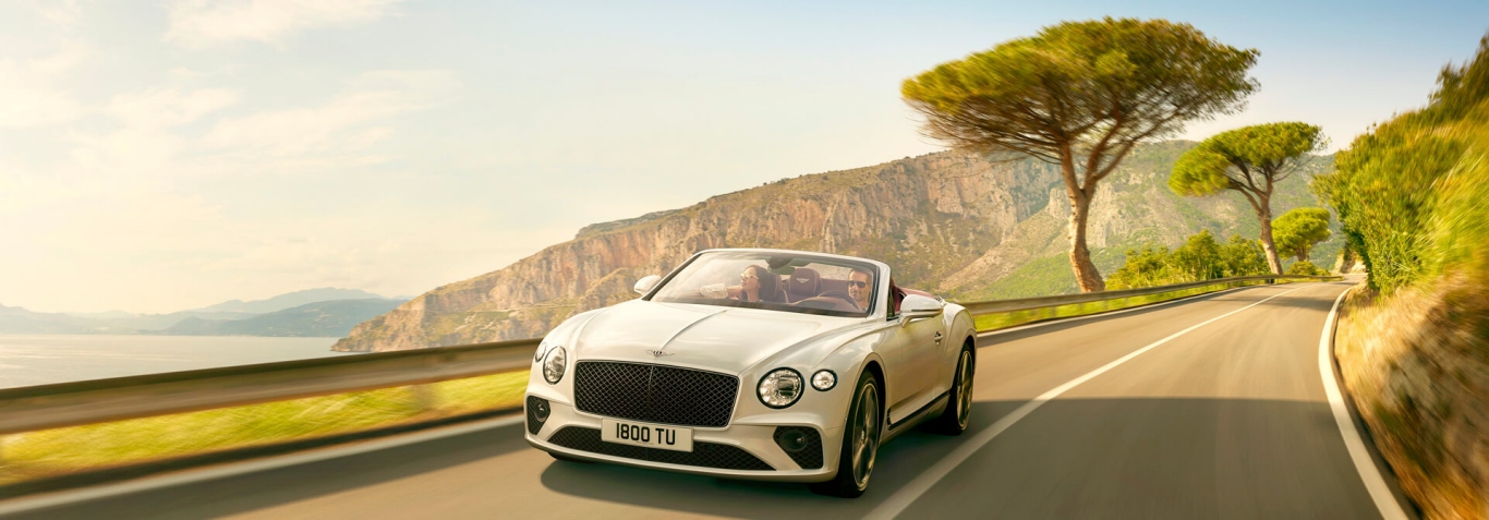 new white Bentley Continental GT Convertible driving by cliffs and sea in Italy 1920x670.jpg